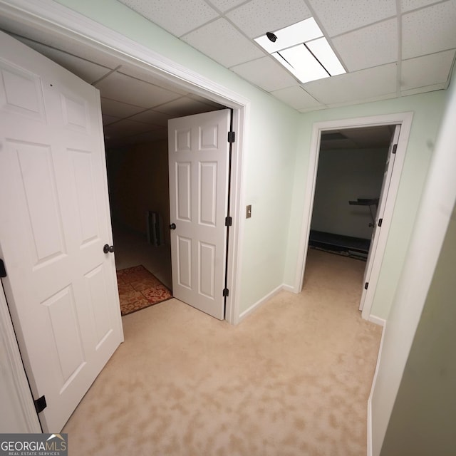 corridor with a drop ceiling and light colored carpet