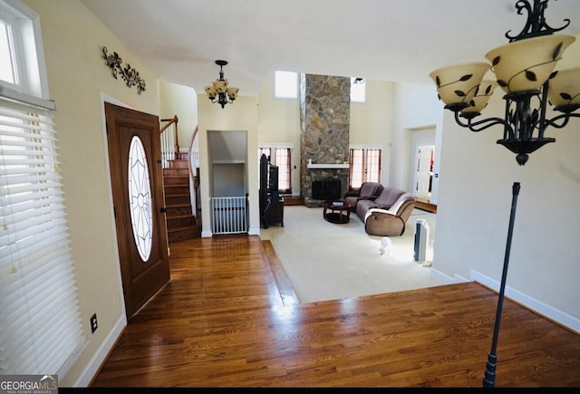 entrance foyer featuring an inviting chandelier, a towering ceiling, a fireplace, and dark hardwood / wood-style flooring