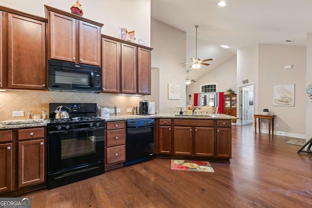 kitchen with dark hardwood / wood-style floors, black appliances, sink, kitchen peninsula, and light stone countertops