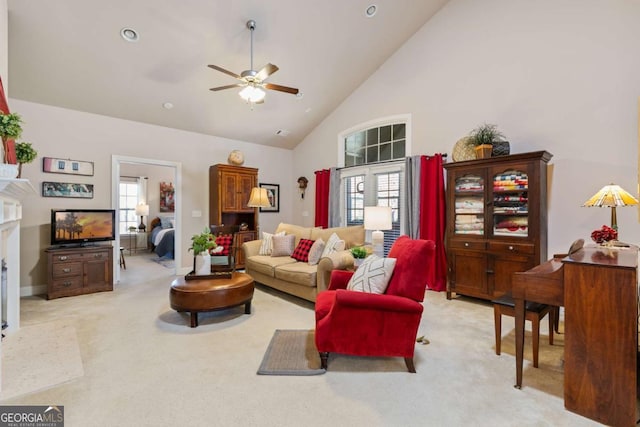 living room with ceiling fan, plenty of natural light, light carpet, and high vaulted ceiling