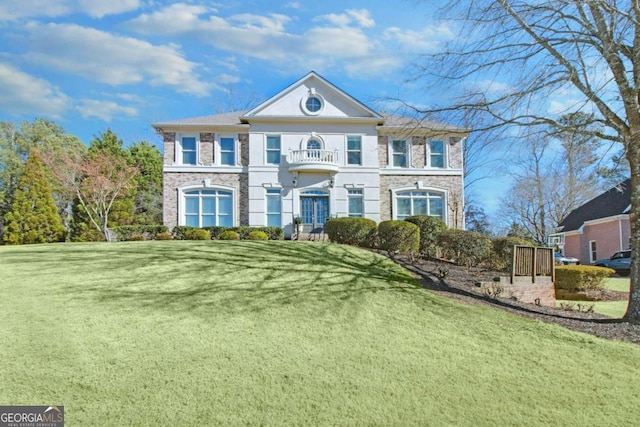 view of front of house featuring a balcony and a front lawn