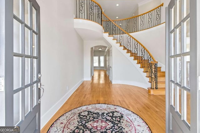 entrance foyer featuring wood-type flooring and a towering ceiling