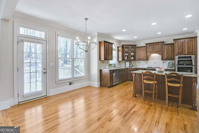 kitchen featuring sink, appliances with stainless steel finishes, a kitchen breakfast bar, a center island, and light stone countertops