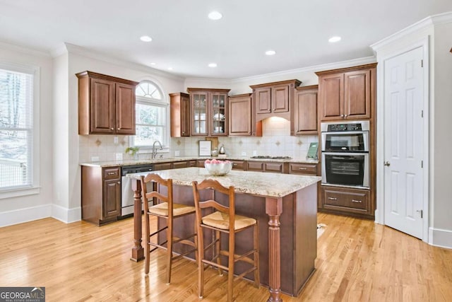 kitchen with a kitchen bar, sink, light stone counters, a center island, and stainless steel appliances