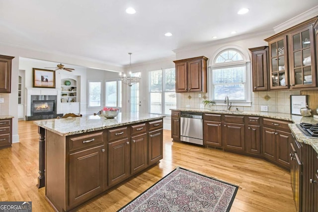 kitchen with sink, crown molding, hanging light fixtures, light hardwood / wood-style flooring, and dishwasher