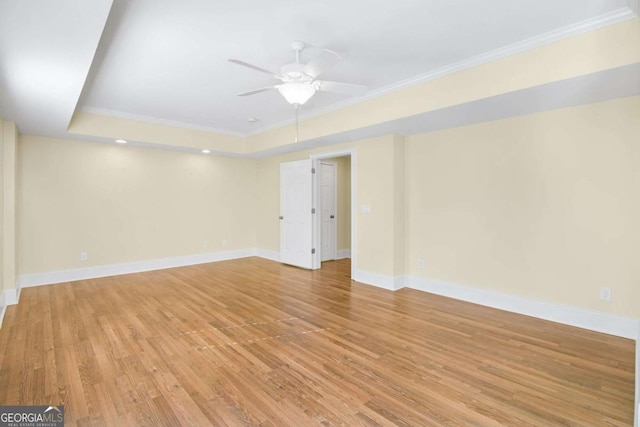 spare room with crown molding, ceiling fan, light wood-type flooring, and a tray ceiling