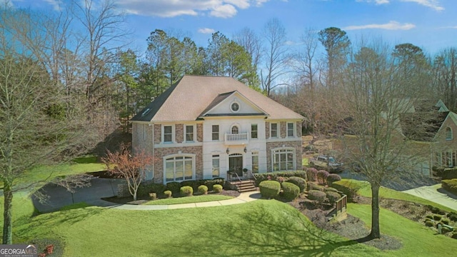 view of front of house featuring a balcony and a front yard