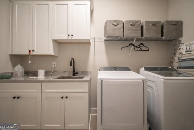 laundry area featuring sink, washing machine and dryer, and cabinets