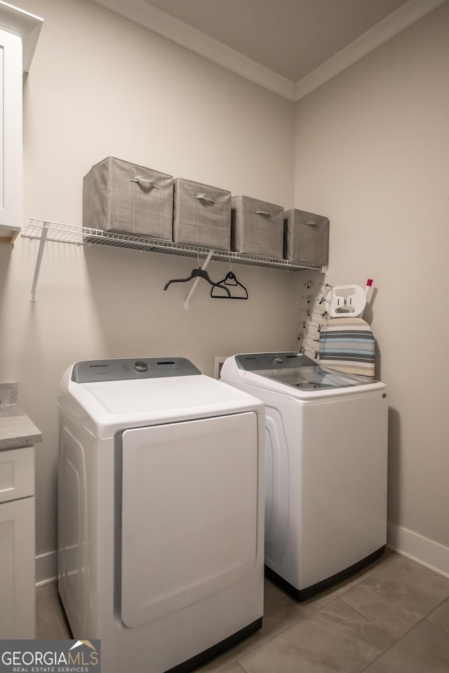 washroom with crown molding, cabinets, and washer and clothes dryer