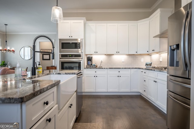 kitchen with stainless steel appliances, dark stone counters, and white cabinets