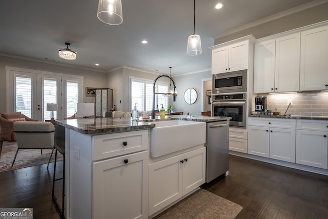 kitchen with appliances with stainless steel finishes, a kitchen breakfast bar, pendant lighting, a kitchen island with sink, and white cabinets