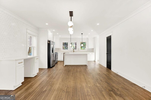 kitchen with white cabinetry, stainless steel appliances, decorative light fixtures, and a kitchen island