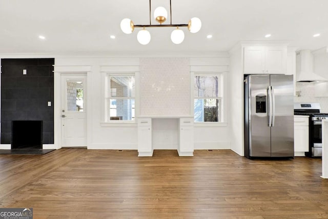 kitchen featuring stainless steel appliances, hanging light fixtures, custom range hood, and white cabinets