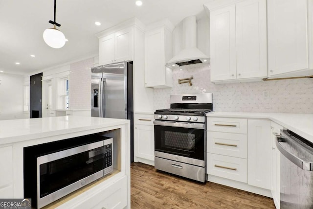 kitchen featuring premium range hood, white cabinetry, hanging light fixtures, stainless steel appliances, and light hardwood / wood-style floors