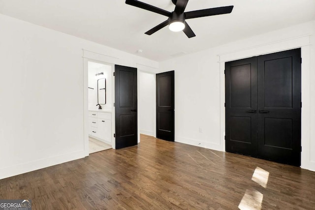 unfurnished bedroom with dark wood-type flooring, ceiling fan, and ensuite bath