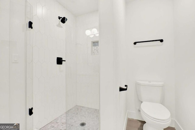 bathroom featuring tiled shower and toilet