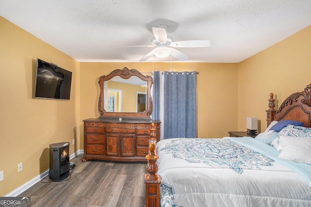 bedroom featuring dark hardwood / wood-style flooring, ceiling fan, and a textured ceiling