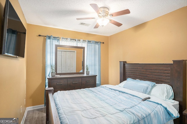 bedroom with ceiling fan, dark wood-type flooring, and a textured ceiling