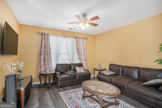 living room with dark wood-type flooring, ceiling fan, and a textured ceiling