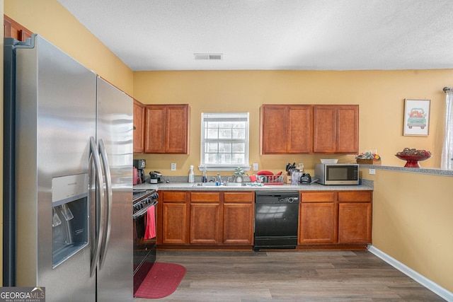 kitchen with sink, stainless steel appliances, dark hardwood / wood-style floors, and a textured ceiling