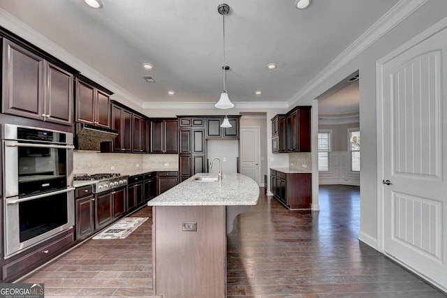 kitchen with dark brown cabinetry, sink, hanging light fixtures, a center island with sink, and stainless steel appliances