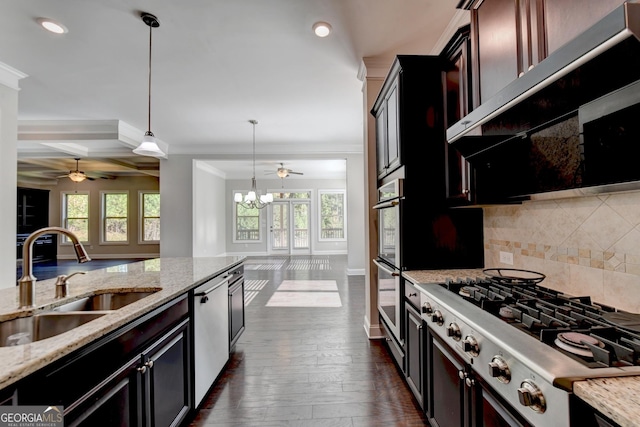 kitchen with light stone counters, sink, decorative light fixtures, and stainless steel appliances