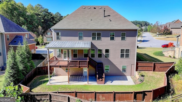 back of house featuring a deck, a patio area, and a lawn