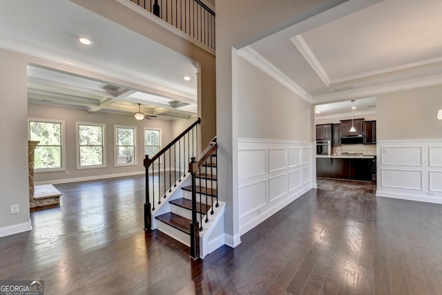 stairway with crown molding, ceiling fan, coffered ceiling, wood-type flooring, and beamed ceiling