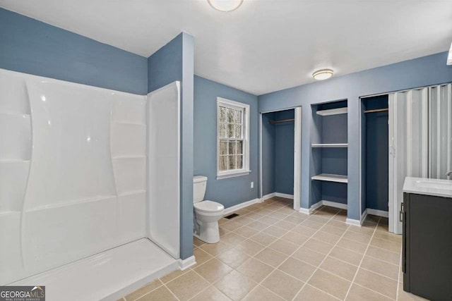 bathroom featuring tile patterned flooring, vanity, a shower, and toilet