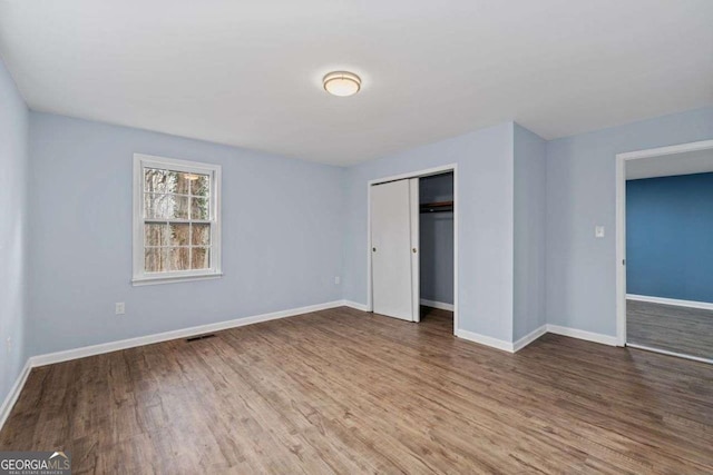 unfurnished bedroom featuring wood-type flooring and a closet