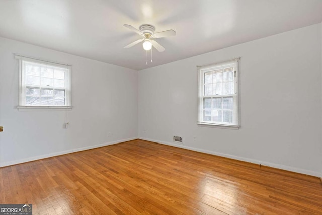 spare room with ceiling fan, a wealth of natural light, and light hardwood / wood-style floors