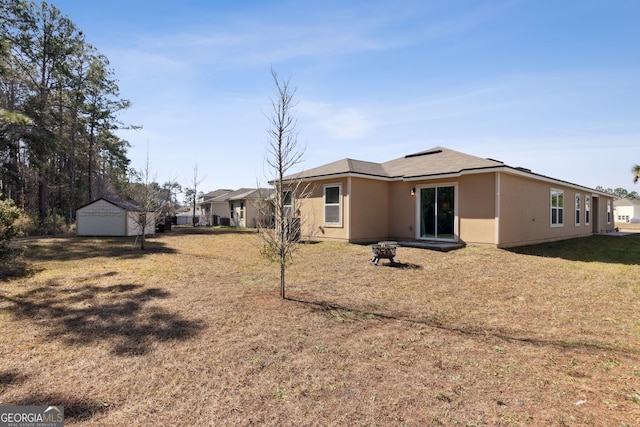 back of house featuring a garage, an outdoor structure, and a lawn