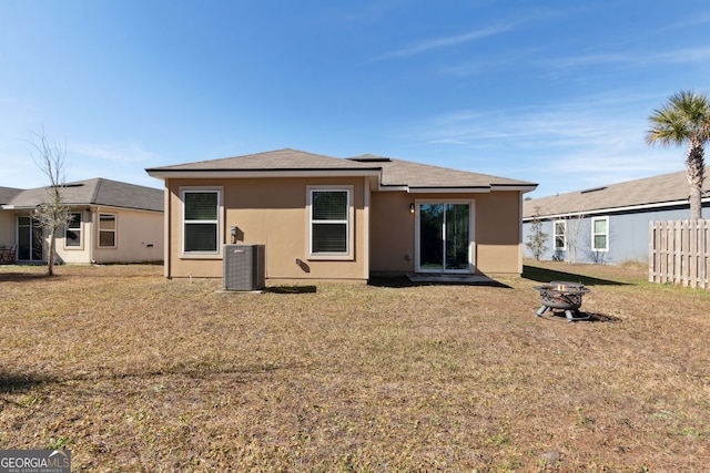 rear view of house featuring a yard, a fire pit, and central air condition unit