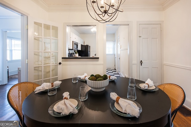 dining area featuring an inviting chandelier, hardwood / wood-style floors, and crown molding