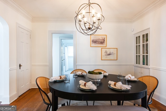 dining area featuring dark hardwood / wood-style flooring, ornamental molding, and an inviting chandelier