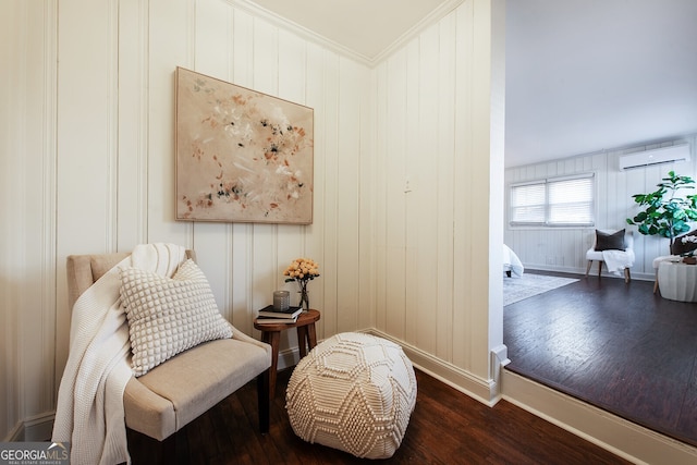 sitting room featuring a wall mounted air conditioner, dark wood-type flooring, and ornamental molding