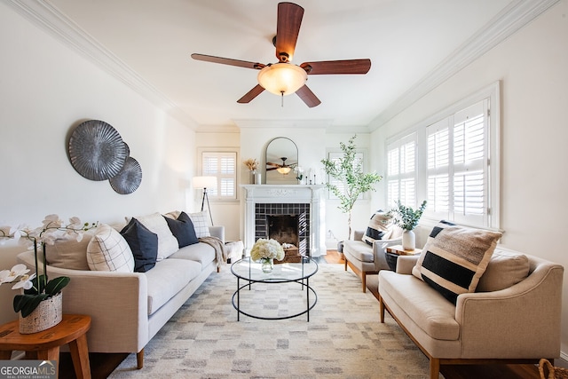 living room with crown molding, ceiling fan, and a tiled fireplace