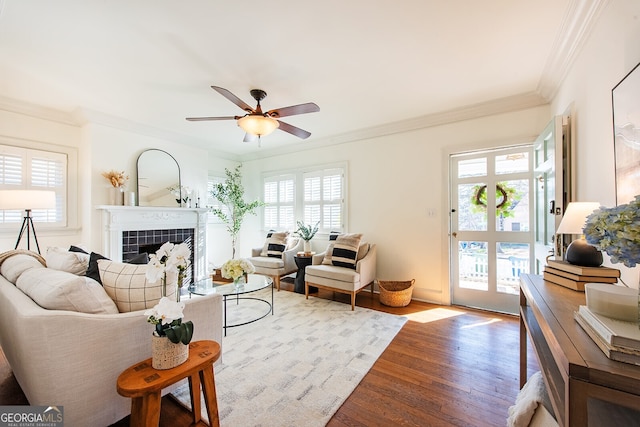 living room featuring a fireplace, ornamental molding, light hardwood / wood-style floors, and ceiling fan