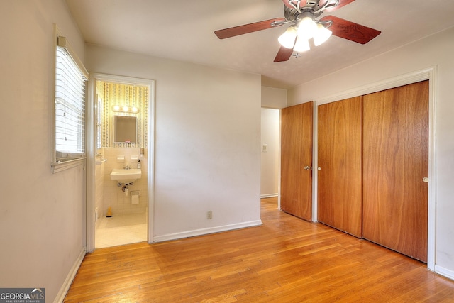 unfurnished bedroom with sink, ceiling fan, ensuite bathroom, light hardwood / wood-style floors, and a closet