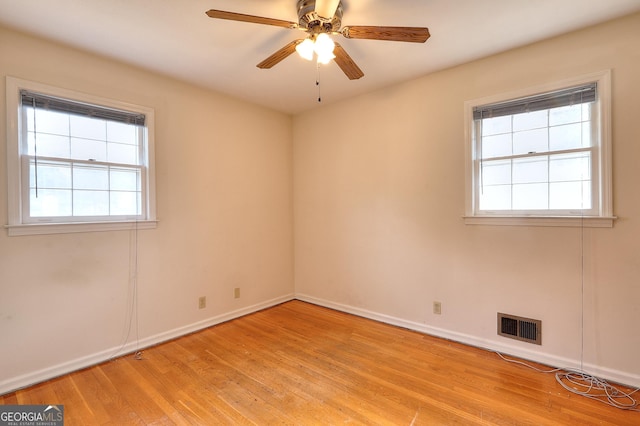 spare room with ceiling fan, a wealth of natural light, and light wood-type flooring