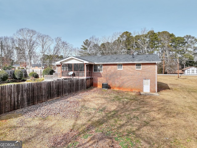 rear view of house featuring a yard, central AC, and a sunroom