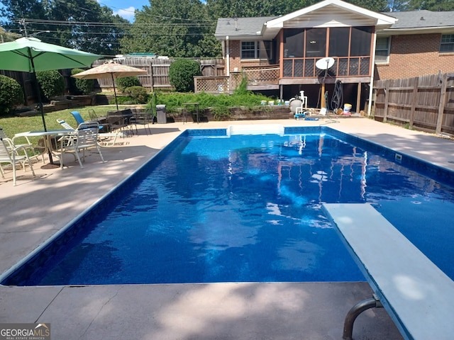 view of pool featuring a sunroom, a diving board, and a patio area