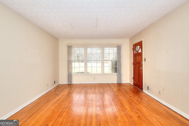 spare room with a textured ceiling and light wood-type flooring