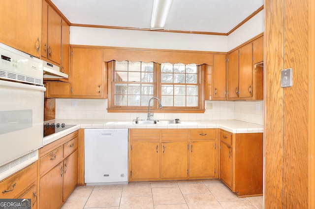 kitchen featuring tasteful backsplash, sink, light tile patterned floors, crown molding, and white appliances