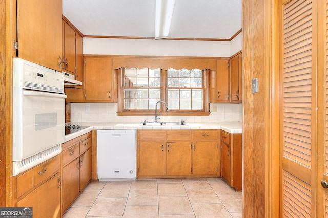 kitchen with tasteful backsplash, white appliances, sink, and light tile patterned floors