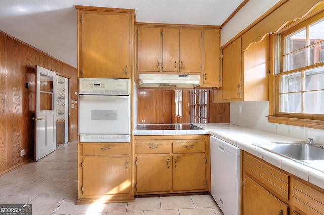 kitchen with light tile patterned flooring, tile countertops, wooden walls, white appliances, and backsplash