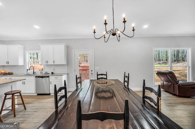 dining area with sink, ornamental molding, light hardwood / wood-style floors, and a chandelier