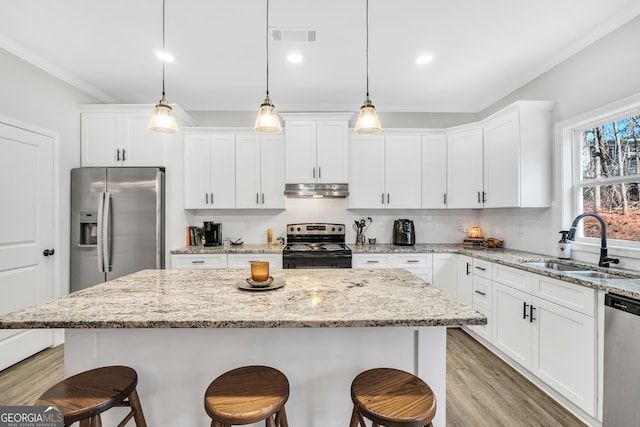 kitchen featuring pendant lighting, stainless steel appliances, sink, and a kitchen island