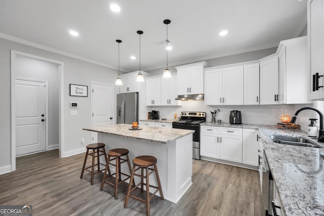 kitchen with white cabinetry, appliances with stainless steel finishes, sink, and a center island