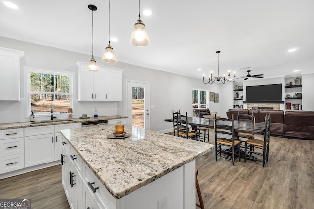 kitchen with a center island, sink, white cabinets, and decorative light fixtures